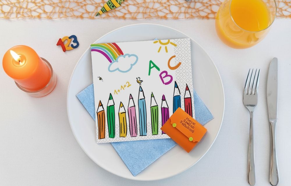 Servietten-Tischdeko zur Einschulung mit bunten Bleistiften, ABC, Regenbogen und einer kleinen Zuckertüte auf einem Teller.