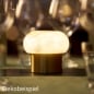 Duni LED-Tischlampe Namak, kabellos und wiederaufladbar, modernes Design, Sockel Messingoptik, auf festlich gedecktem Tisch, warmes stimmungsvolles Licht.
