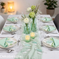 Festlich gedeckter Tisch in Weiß und Mintgrün mit Fisch-Deko, Blumenvasen und Kerzen.