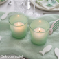 Zwei brennende Teelichter in mintgrünen Glas-Windlichtern auf einem Stoff Tischläufer in Mint.