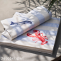 Aufeinanderliegende Servietten mit Hummer-Print, Rückseitig mit Fisch-Print im natürlichen Schattenwurf einer Palme.