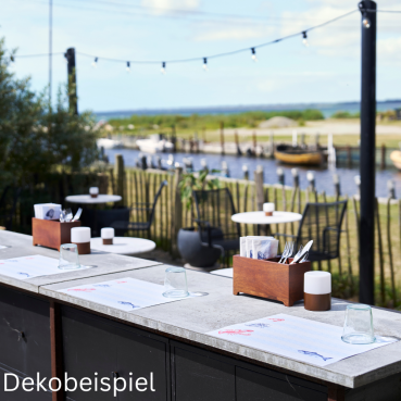 Maritimes Papier-Tischset mit detailreichen Meeresmotiven wie Hummer und Krabbe auf Betontischplatte mit Blick auf die Natur.