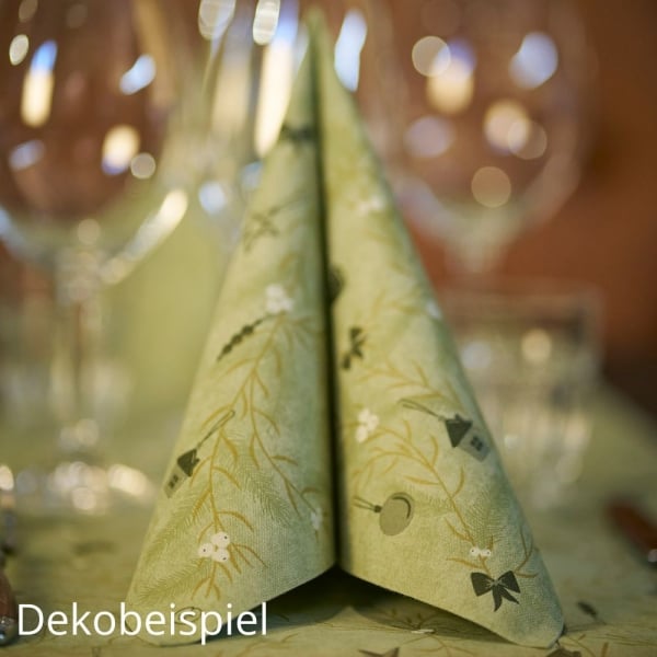 Gefaltete Premium-Serviette in Pistaziengrün aus der Weihnachtsserie Duni Noël Pistachio auf festlich gedecktem Tisch mit Gläsern im Hintergrund.