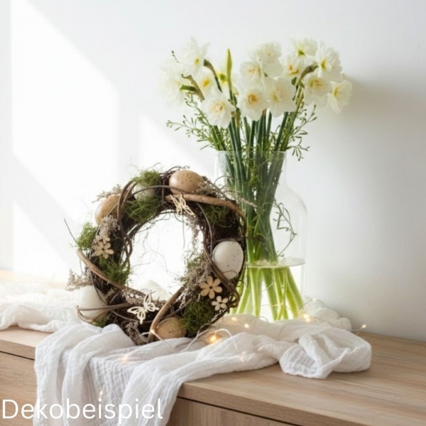 Frühlingshafte Osterdeko: Ein Naturkranz mit Moos und Eiern neben weißen Narzissen in einer Vase.